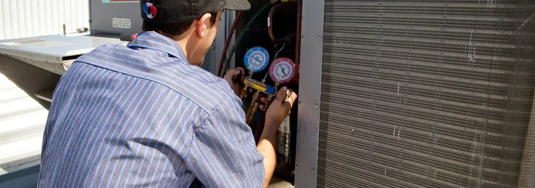HVAC technician servicing a condenser unit in Big Lake